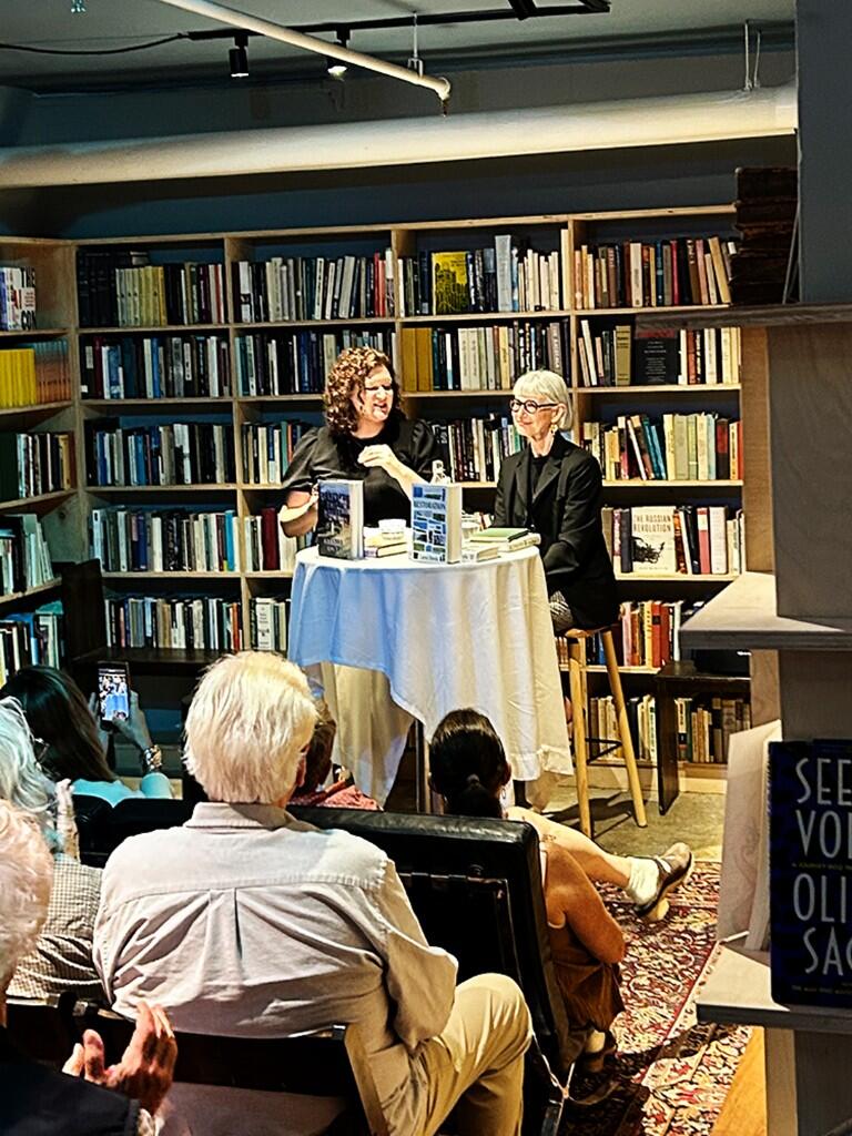 Amanda Hule speaking at a bookstore reading in front of bookshelves